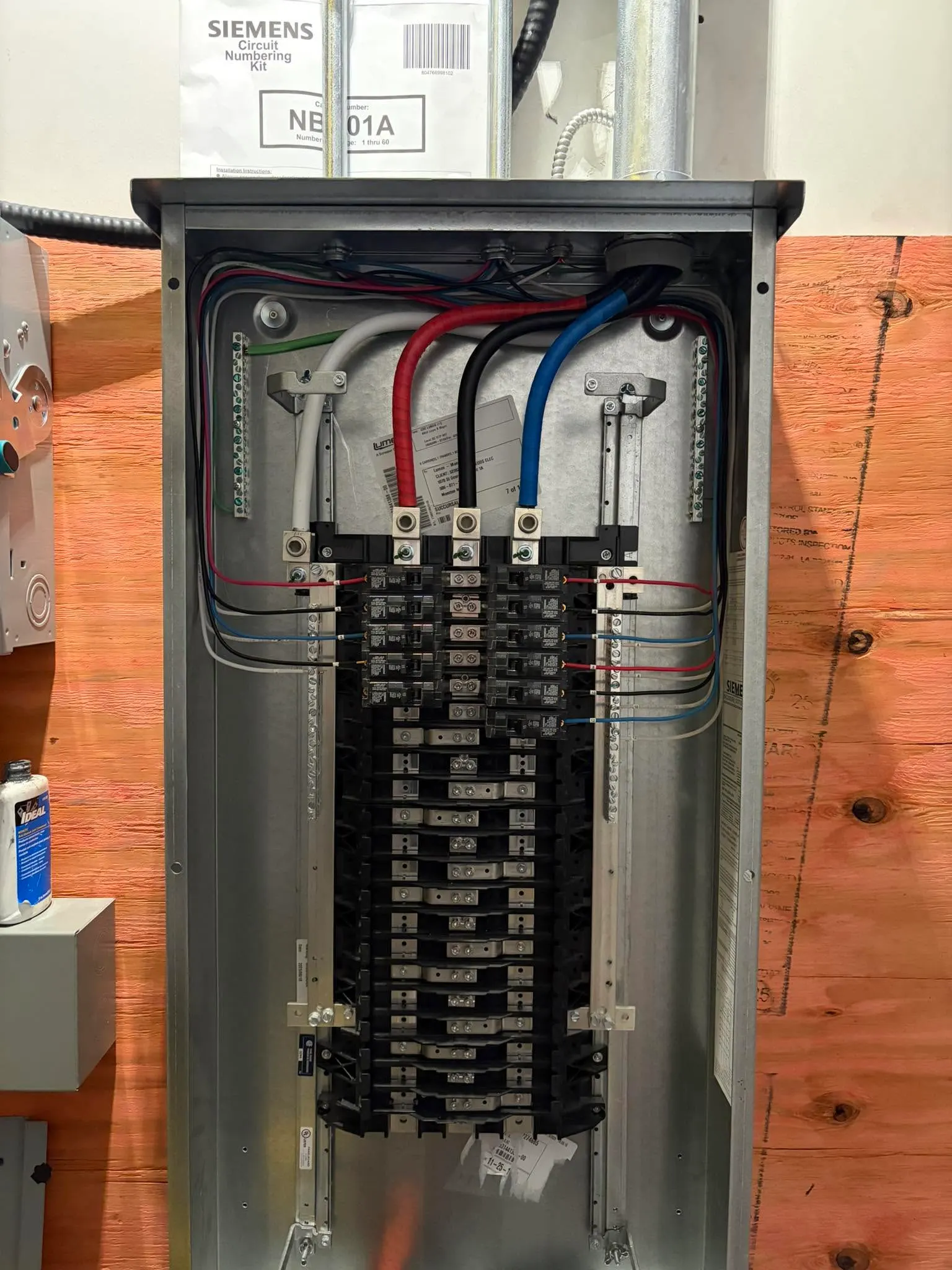 Open commercial distribution panel with colour-coded conductors landed on the main lugs and neatly formed branch circuits
